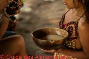 Fille indigène Wayuri offrant un bol de boisson Chicha à un touriste en Amazonie équatorienne